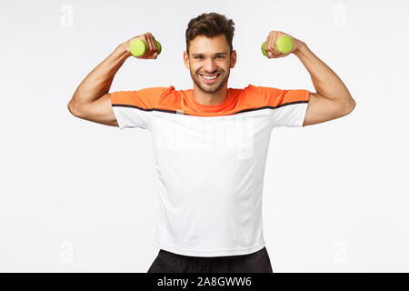 Sport, diet and healthy lifestyle concept. Handsome smiling, happy sportsman enjoy workout, proudly showing his muscles, lift arms and tense biceps to Stock Photo