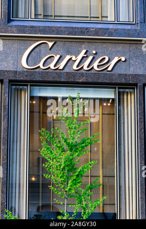 The Boutique Cartier Tokyo Ginza building detail. Front display window with springtime tree in foreground in front and Cartier logo above. Stock Photo