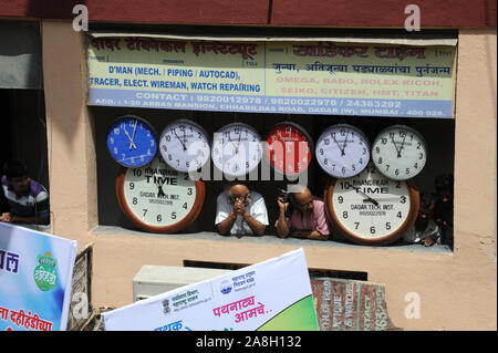 Maharashtra, Mumbai, India, Southeast Asia -Two men standing near wall clock watching Human Pyramid trying to break dahi handi on Janmashtami festival Stock Photo