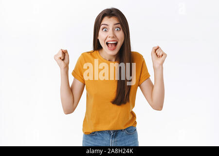 Happy, excited and relieved young woman heart amazing news, fist pump, raise clenched hands in joy and amazement, stare camera surprised, scream from Stock Photo