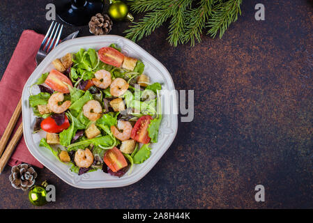 Fresh caesar salad with shrimps on white plate dark stone table background with Christmas Festive Decoration. Healhty Food Snack Concept. Top view Cop Stock Photo