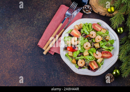 Fresh caesar salad with shrimps on white plate dark stone table background with Christmas Festive Decoration. Healhty Food Snack Concept. Top view Cop Stock Photo