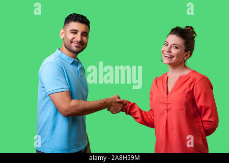 Portrait of lovely young couple in casual wear standing, looking at camera with smile and shaking hands, friendly meeting or acquaintance, greeting. i Stock Photo