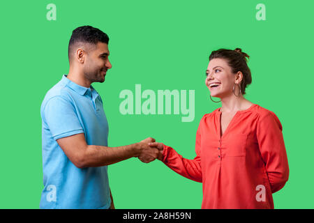 Nice to meet you! Portrait of happy young couple in casual wear standing, smiling at each other and shaking hands, friendly meeting or acquaintance. i Stock Photo