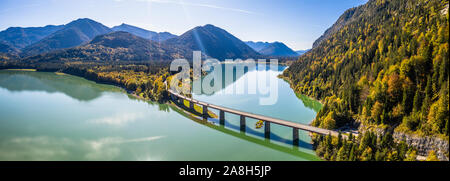 Scenic aerial view of the bridge over Lake Sylvenstein with beautiful reflections. Alps Karwendel Mountains in the back. Autumn scenery of Bavaria Stock Photo