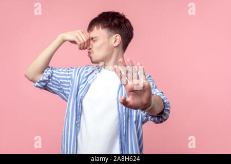 Stop this bad smell! Portrait of annoyed displeased brown-haired man with small beard in casual shirt pinching his nose, disgusted with unpleasant odo Stock Photo