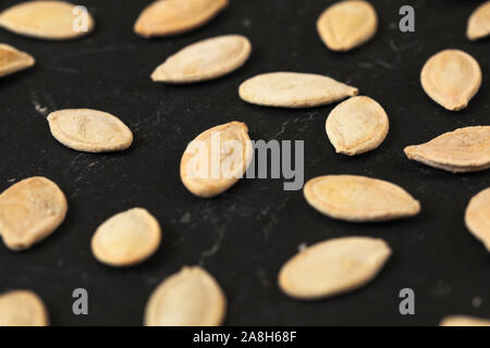 Roasted and salted pumpkin seeds on black board, shallow depth of field photo Stock Photo