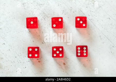 Overhead shot - red translucent playing dices showing all numbers from 1 to 6 on white concrete board Stock Photo