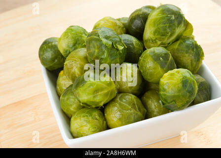 Boiled brussels sprouts in a white square bowl with a cutting board background. Selective Focus with a shallow definition of field. Stock Photo