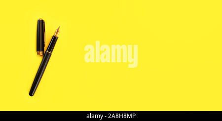 Classic black and gold fountain pen, opened, yellow background, view from above, banner with space for text right Stock Photo