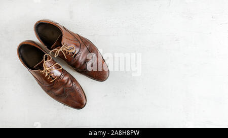 Top down view, worn classic dark brown brogue shoes on white board. Wide banner with space for text right. Stock Photo