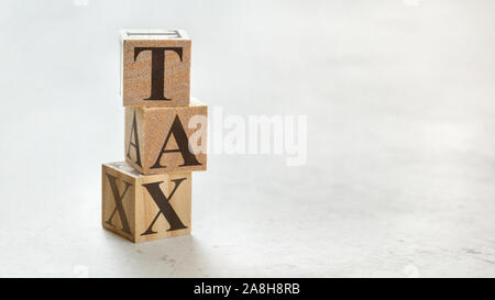 Pile with three wooden cubes - letters TAX on them, space for more text / images at right side. Stock Photo