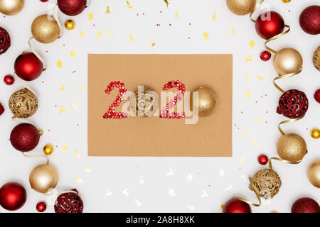 2020 made of red sparkles and decorative golden christmas ballls on craft sheet of paper. Frame from christmas balls. Happy new year 2020 concept. Stock Photo