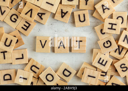 Top down view, pile of square wooden blocks with letters VAT (stands for Value added tax) on white board. Stock Photo