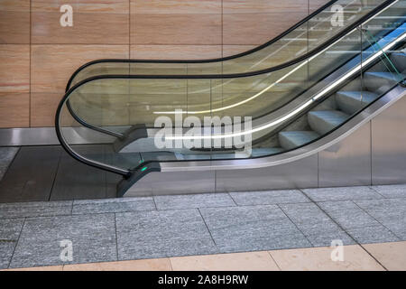 Escalator in modern building, side view with marble wall in background. Stock Photo