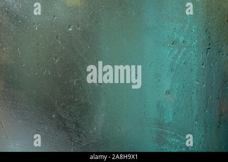 Wet glass on bus window, blurred green scene behind, abstract steamy / dew condensation background Stock Photo