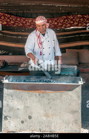 WADI RUM, JORDAN-FEBRUARY 2015. Arab man cooking a meat barbecue. Stock Photo