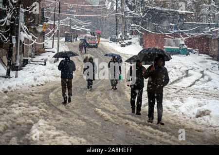 Kashmir, India. 09th Nov, 2019. Residents walk along a snow covered road while holding umbrellas during the heavy snowfall in Kashmir.At least seven people died in different incidents at many places of the valley during seasons first snowfall. A Meteorological Department has predicted dry weather in the region for the next one week. Credit: SOPA Images Limited/Alamy Live News Stock Photo