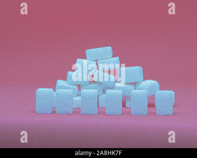 sugar cubes on top another in front of different colors Stock Photo