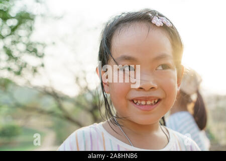 Portrait of Asian cute child on outdoor activity, smiling face, background of blurred nature, sunlight from behind. Stock Photo