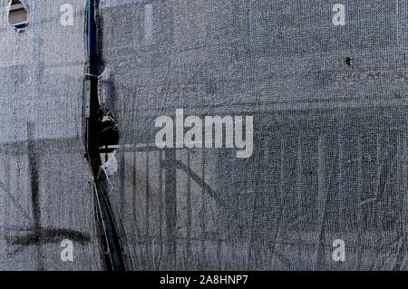 Detail of a rusty scaffolding through a white plastic fiber net - Abstract background (Pesaro, Italy, Europe) Stock Photo