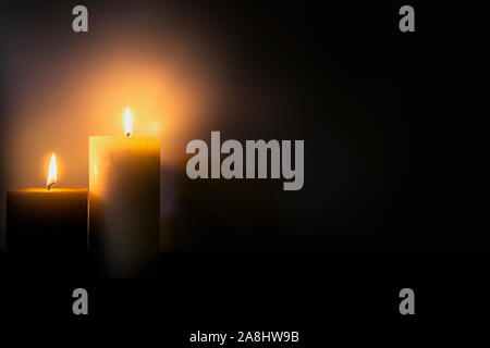 Two burning brightly candles in the dark shadow, space for text romantic colorful concept background Stock Photo