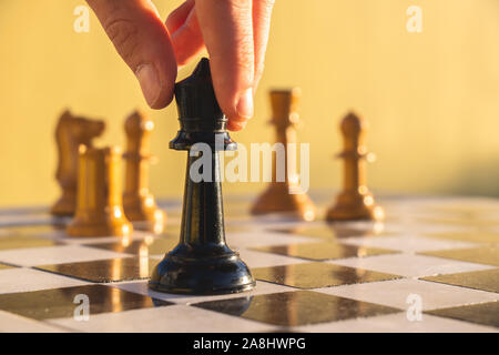 Fingers moving a chess piece on a chess board in a park. Stock Photo