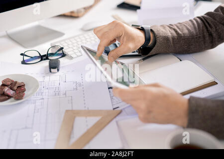 Hands of contemporary engineer with touchpad looking through electronic data Stock Photo