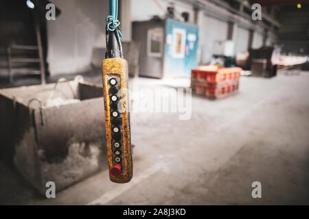 Shallow depth of field (selective focus) image with a worn out suspended industrial control panel with switches in a factory. Stock Photo