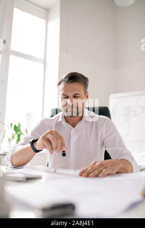 Mature engineer with dividers making new sketch of architectural construction Stock Photo