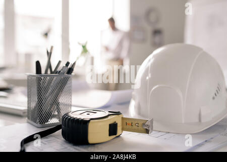 Workplace of engineer with hardhat, measuring tape, bunch of pencils and sketch Stock Photo