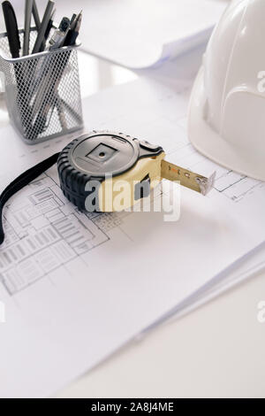 Measuring tape, bunch of pencils and sketches on workplace of modern architect Stock Photo