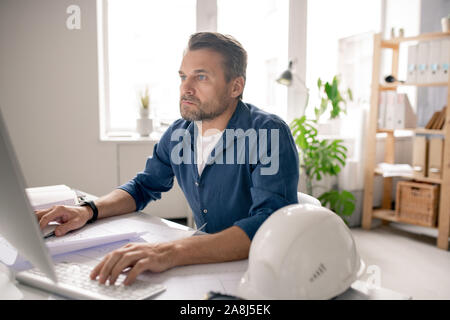 Serious engineer concentrating on work while sitting in front of computer screen Stock Photo