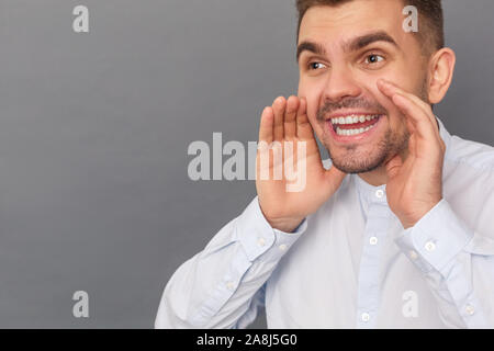 Freestyle. Young man studio standing isolated on grey smiling screaming close-up Stock Photo