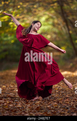 Young teenage girl in red dress dancing in the forest Stock Photo