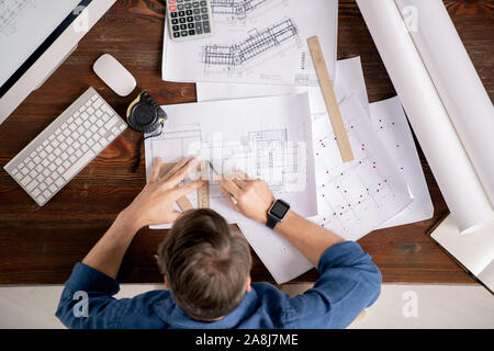 Overview of busy engineer with ruler and pencil drawing line on sketch Stock Photo