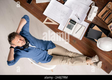 Top view of relaxed engineer in casualwear enjoying break by workplace Stock Photo
