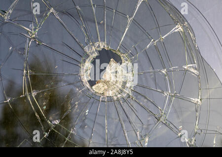 Window pane hit by a stone and broken in a spiderweb pattern Stock Photo