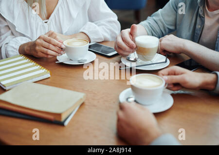 Hands of college friends gathered by table in cafe after classes for a drink Stock Photo