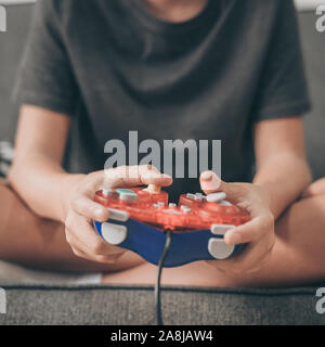 Closeup view of young hands playing with a console remote controller. Fingers on joystick of a colorful gamepad. Addicted gamer enjoy with video game Stock Photo