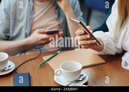 Hand of young mobile woman with smartphone scrolling through contacts Stock Photo