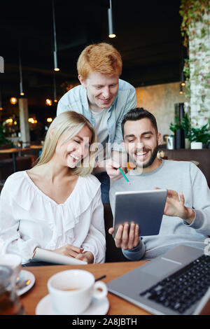 Group of young college students laughing at funny stuff on touchpad display Stock Photo