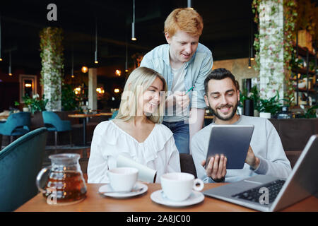 Young students using touchpad and laptop while searching for information Stock Photo
