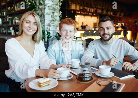 Restful happy students of college sitting by table in cafe after classes Stock Photo