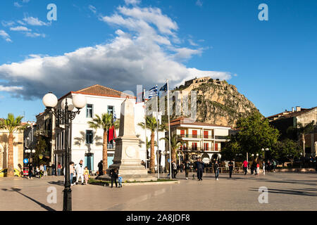 Nafplion, Greece - May 4 2019: People wander around the main town square in Nafplio with its famous Byzantine castle in the Peloponnese. Stock Photo