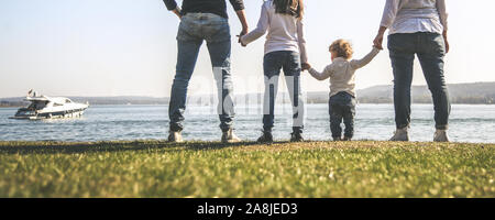 All family together holding hands near the sea. Four people standing on the seashore in a beautiful sunny day. Mother, father and two daughters Stock Photo