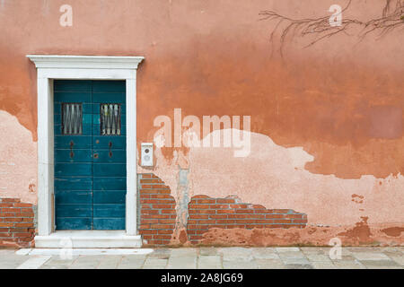 Vintage front door painted blue and a wall with old weathered render in Venice, Italy Stock Photo