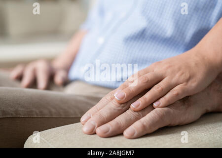 Hand of young affectionate and careful woman on that of her senior father Stock Photo