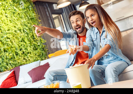 Young adult woman and man with excited faces watching tv Stock Photo