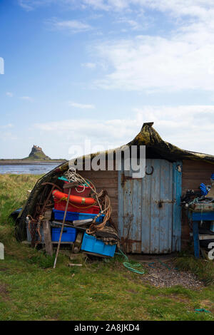 Looking towards Lindisfarne Castle from one of the fishing boat sheds at Holy Island in Northumberland on a sunny day in early spring. Stock Photo